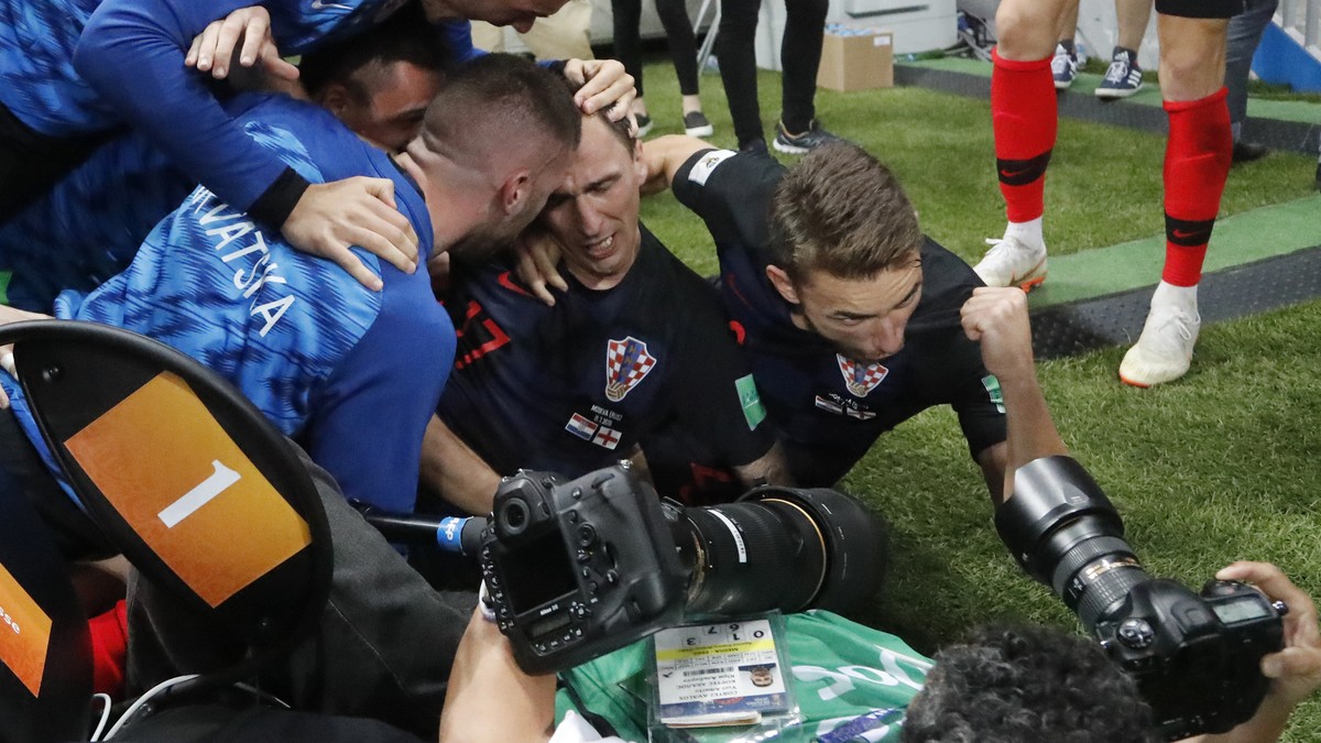 Croatia's Mario Mandzukic sits between his teammates after falling over a photographer when celebrating after scoring his side's second goal during the semifinal match between Croatia and En ...