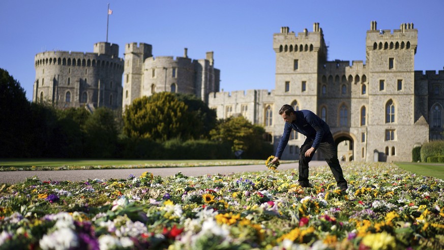 Workers from the Crown Estate move the floral tributes laid by members of the public outside Windsor Castle onto Cambridge Drive, near the Long Walk, Windsor, Sunday Sept. 18, 2022 ahead of the funera ...
