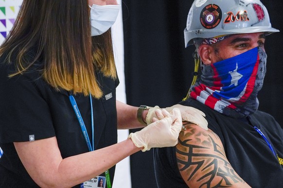 epa09135787 Local 28 Sheet Metal Worker Demetrius Buttelman (R) is inoculated with the first dose of the Pfizer COVID-19 vaccine during an event with New York Governor Andrew Cuomo at a pop-up vaccina ...