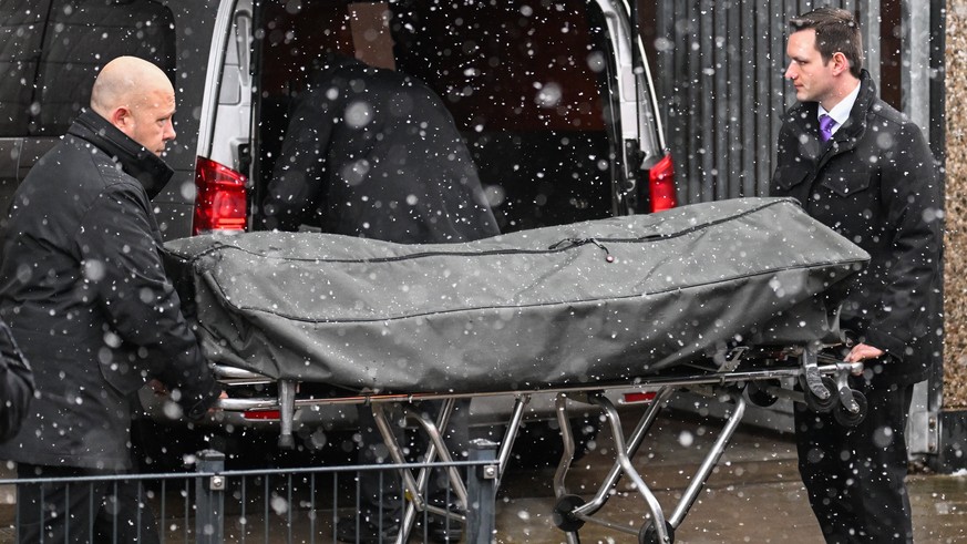 epa10513234 Funeral directors treat a body on a stretcher at the scene of a shooting in Hamburg, Germany, March 10, 2023. At least eight people have died, including the suspected gunman, and ...