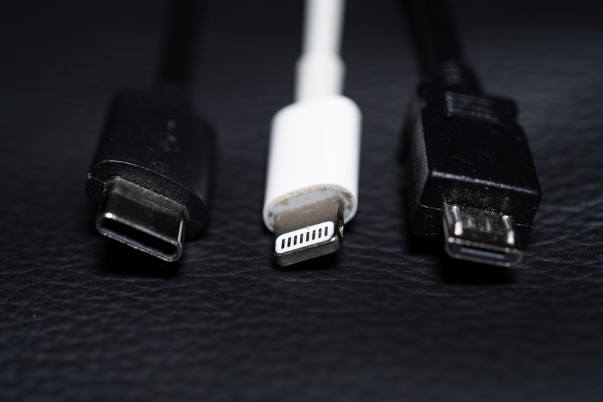 ARCHIV - 22.09.2021, Niedersachsen, Oldenburg: Ein USB-C (l-r), ein Apple Lightning und ein Micro-USB Kabel (l-r) liegen nebeneinander zu sehen. (zu dpa &quot;Einigung auf einheitliche Ladekabel in de ...