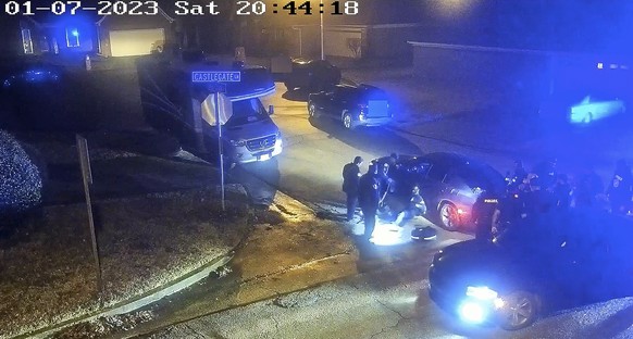 FILE - In this image from a video released by the City of Memphis, paramedics stand near Tire Nichols, sitting leaning against a car, while police officers, right, stand on the scene after a brutal assault...