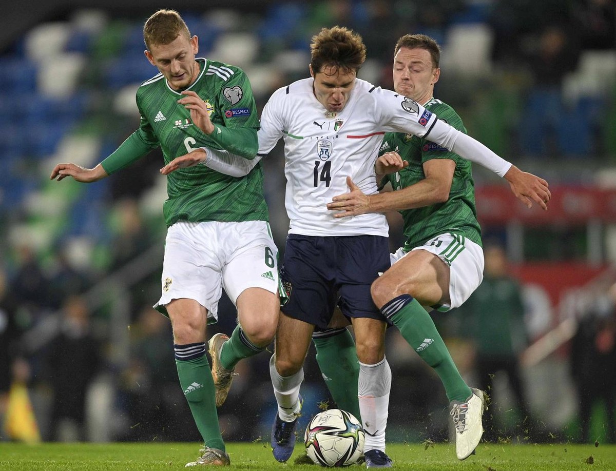 epa09584022 Italy's Federico Chiesa (C) in action against Northern Ireland's George Saville (L) and Jonny Evans (R) during the FIFA World Cup 2022 group C qualifying soccer match between Nor ...