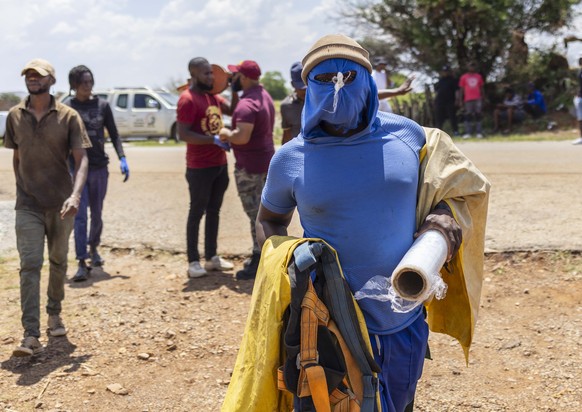 epa11728852 A community member wears a mask preparing to assist trapped miners near the entrance to a disused gold mine shaft in Stilfontein, around 150 kilometers south-west of Johannesburg, South Af ...