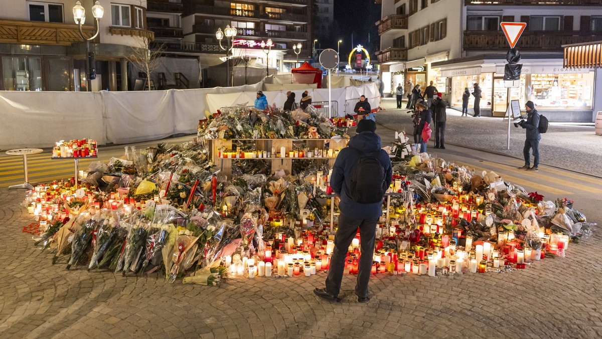 epa12629510 Flowers and candles are pictured in tribute to the victims after the fire at the 'Le Constellation' bar and lounge in Crans-Montana, Switzerland, 05 January 2026. At least 40 peo ...