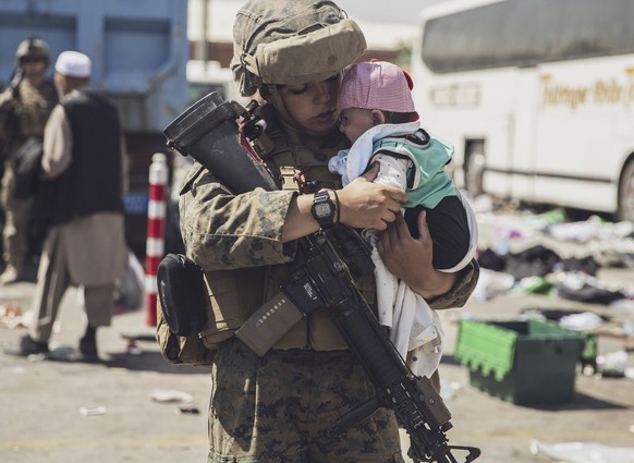 In this image provided by the U.S. Marine Corps, a Marine with the 24th Marine Expeditionary Unit (MEU) carries a baby as the family processes through the evacuation control center at Hamid Karzai Int ...