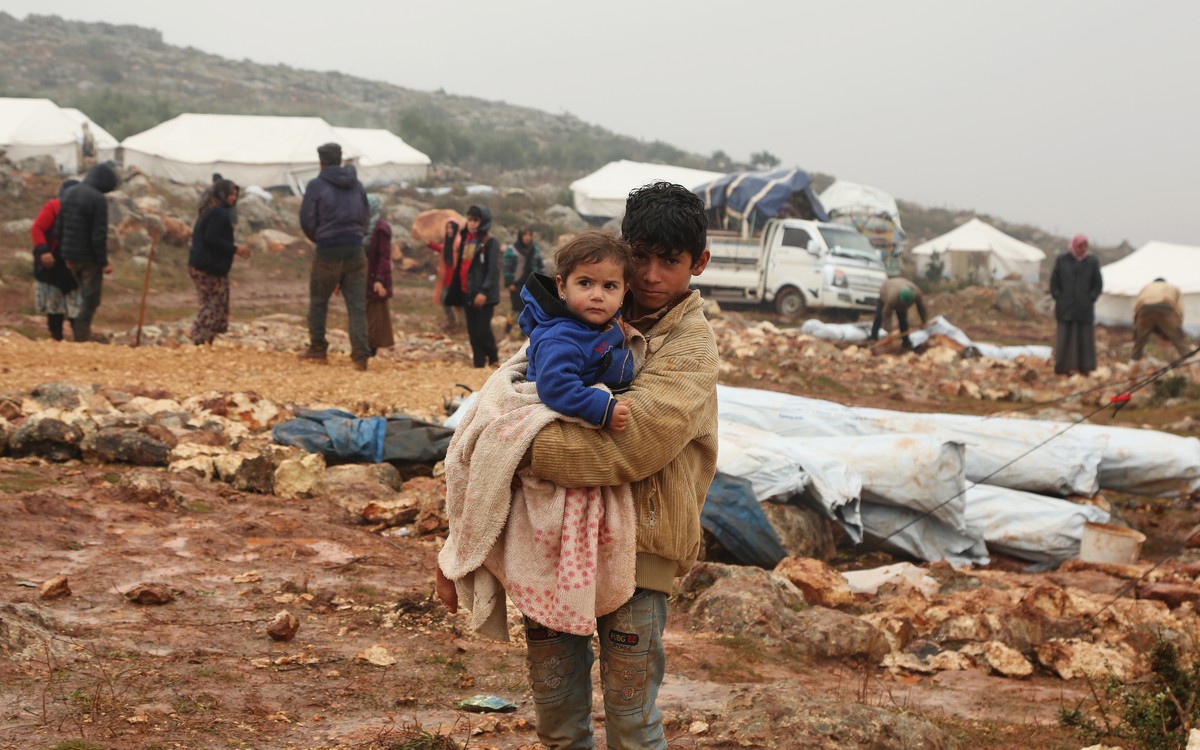 epa08100426 Displaced Syrian children look on as adults set up tents, after fleeing violence of Maarat al-Numan town, near the Turkish border, Northern Syria, 28 December 2019 (issued 03 January 2020) ...