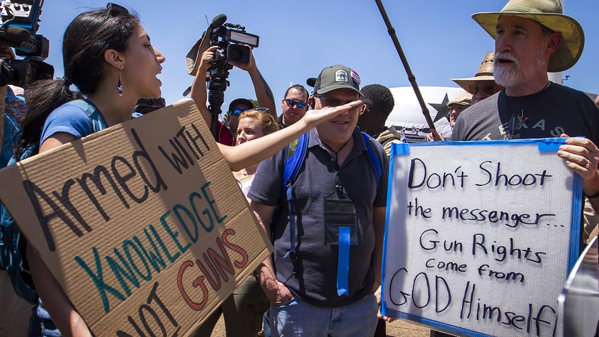 Gun rights advocate Drew Deal of Dallas, right, discusses the second amendment with a gun control advocate who would not give her name as dueling groups demonstrated outside Dallas City Hall during th ...