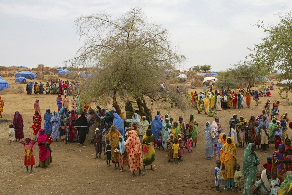 FILE - Sudanese displaced people gather at the Zam Zam refugee camp outside the town of El-Fashir in the Darfour region of Sudan, during a visit by U.N. officials, on July 1, 2004. The U.N. humanitari ...