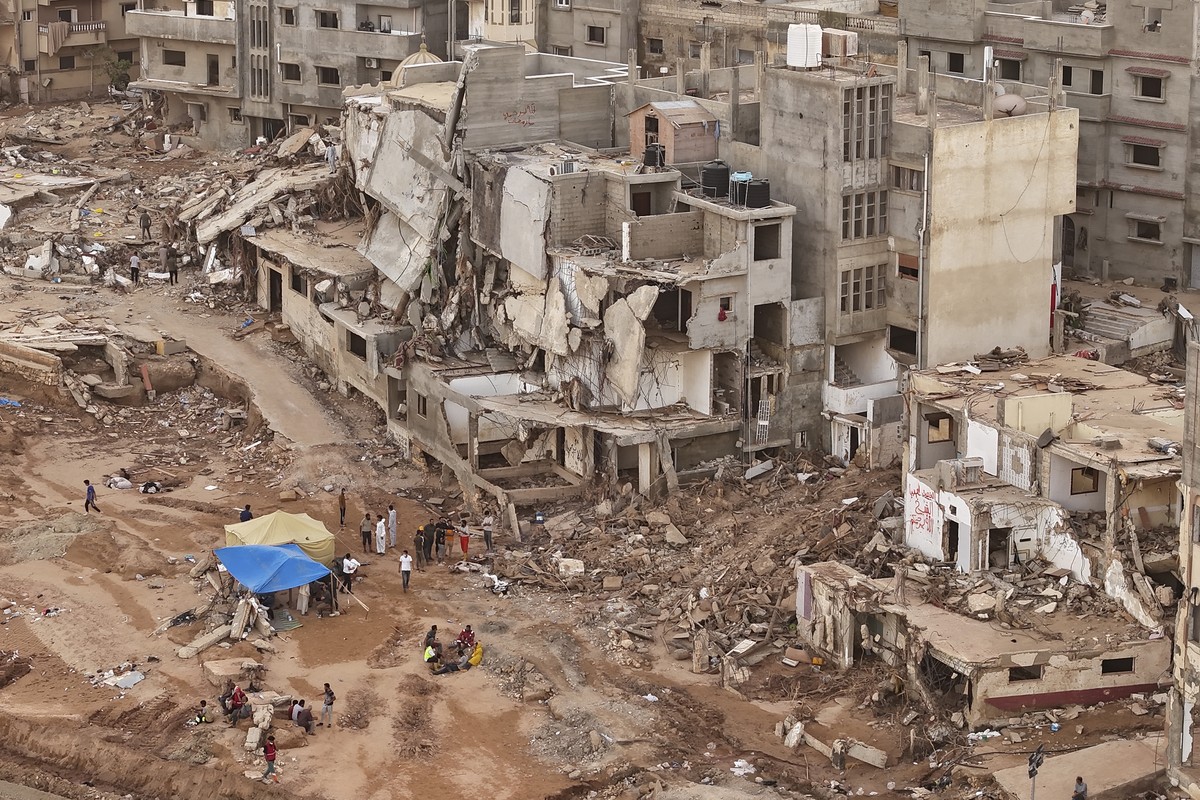 Rescuers and relatives sit in front of collapsed buildings after recent flooding caused by Mediterranean storm Daniel, in Derna, Libya, Monday, Sept. 18, 2023. Derna flood survivor Abdul Salam Anwisi  ...