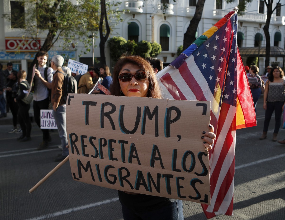 A woman holds a sign that reads in Spanish "Trump, respect migrants" during a march called by a local women's movement against U.S. President Donald Trump in Mexico City, Friday, Jan. 2 ...