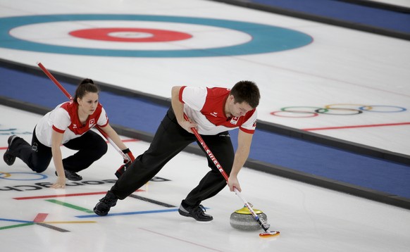 Switzerland Martin Rios, right, sweeps the ice as teammate Jenny Perret watches him during a mixed doubles curling match against Canada&#039;s Kaitlyn Lawes and John Morris at the 2018 Winter Olympics ...