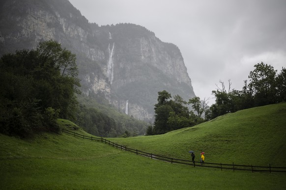 Menschen mit Schirm sind unterwegs zu den Seerenbachfaelle, am Montag, 28. Juli 2025, bei Betlis in Amden. Die Seerenbachfaelle fuehren ueber drei Stufen und haben eine Gesamthoehe von 585 Metern. Im  ...