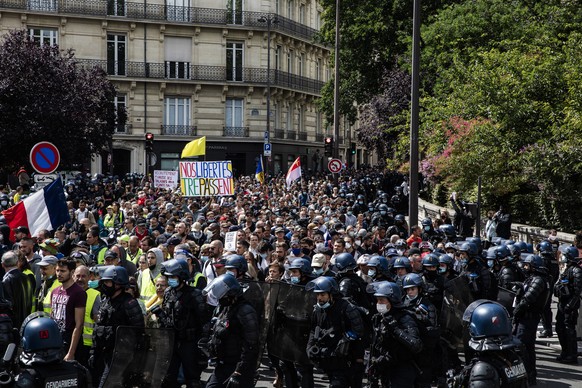 A man holds a poster on which is written : &quot;our liberties pass away&quot;, amidst the crowd, during a protest against the vaccine and vaccine passports, in Paris, France, Saturday Aug. 7, 2021. S ...