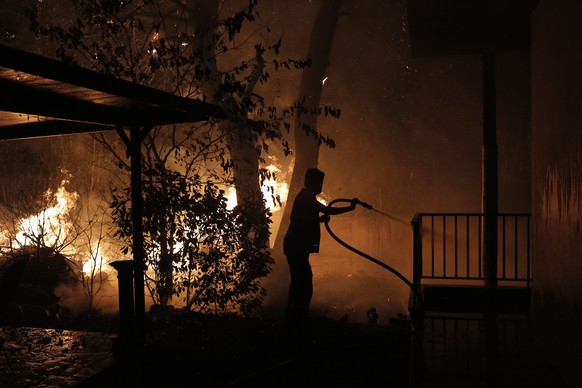 epa09399556 A volunteer battles flames burning a house in the area of Afidnes near Athens, Greece, 05 August 2021 (issued 06 August 2021). Firefighters are relying on help by air, as very high tempera ...