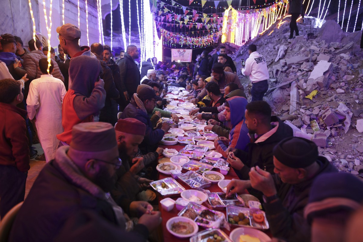 Palestinians hold a collective suhoor meal next to their destroyed homes for the holy month of Ramadan in Khan Younis, southern Gaza Strip, Friday, Feb. 28, 2025. Arabic reads: "Ramadan." (A ...