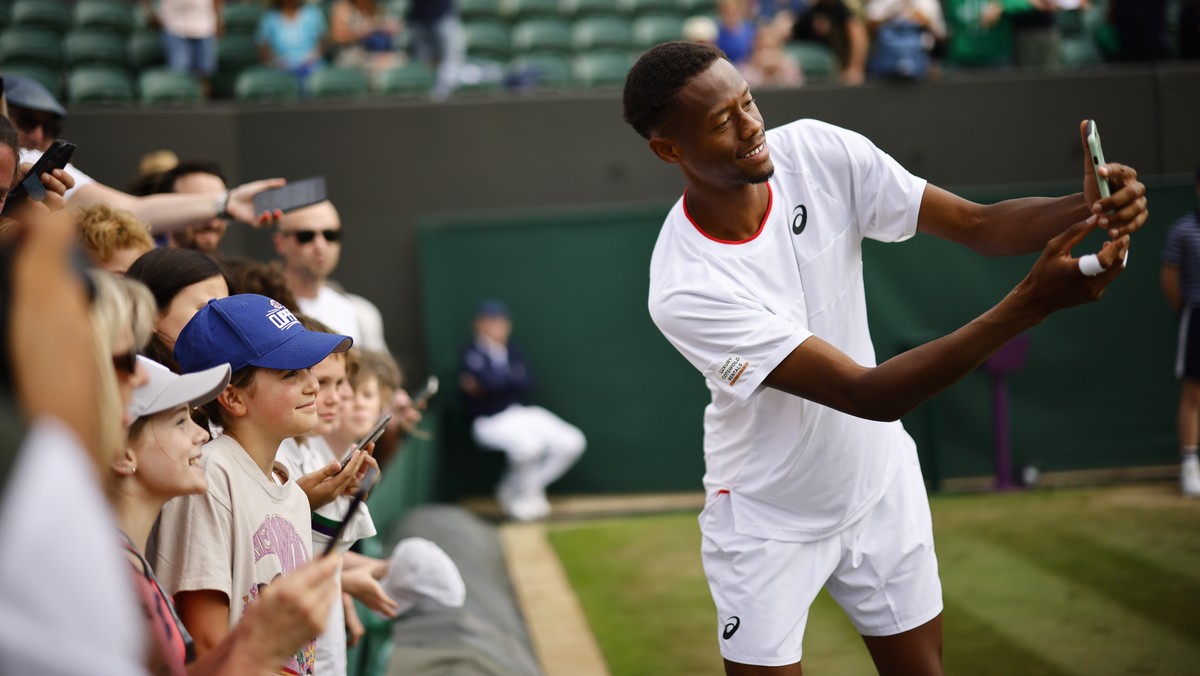 epa10738110 Christopher Eubanks of USA poses for selfies with fans after winning his Men's Singles 4th round match against Stefanos Tstsipas of Greece at the Wimbledon Championships, Wimbledon, B ...