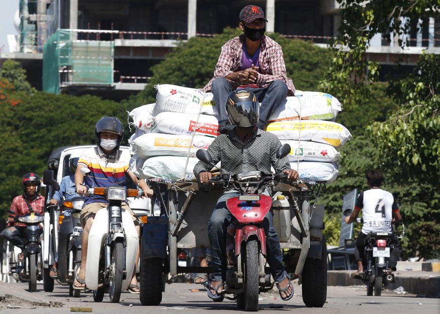 epaselect epa08544502 People wear face masks as they ride motorbikes on a street in Phnom Penh, Cambodia, 14 July 2?020. Many Cambodians continue to wear face masks in public as a precautionary measur ...