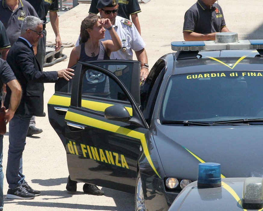 Sea-Watch 3 captain Carola Rackete, center, from Germany, enters an Italian finance police car as she arrives in the Sicilian port of Porto Empedocle, from the island of Lampedusa, Italy, Monday, July ...