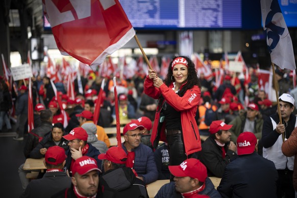 Eine Demonstrantin protestiert mit einer Fahne waehrend einer Verpflegungspause im Zuercher Hauptbahnhof waehrend eines Demonstrationszugs zum Hauptsitz des Baumeisterverbands, am Freitag, 11. Novembe ...