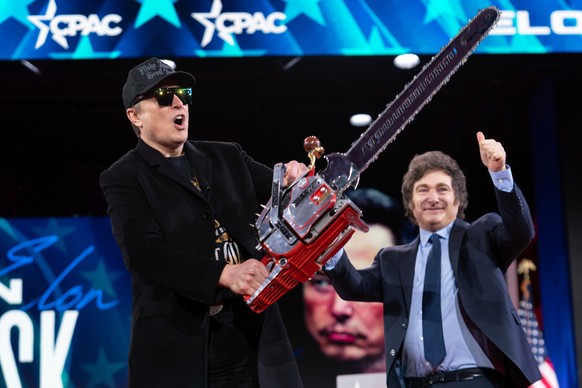 FILE - Elon Musk holds up a chainsaw he received from Argentina's President Javier Milei, right, as they arrive to speak at the Conservative Political Action or CPAC Conference in Oxon Hill, Md.  ...