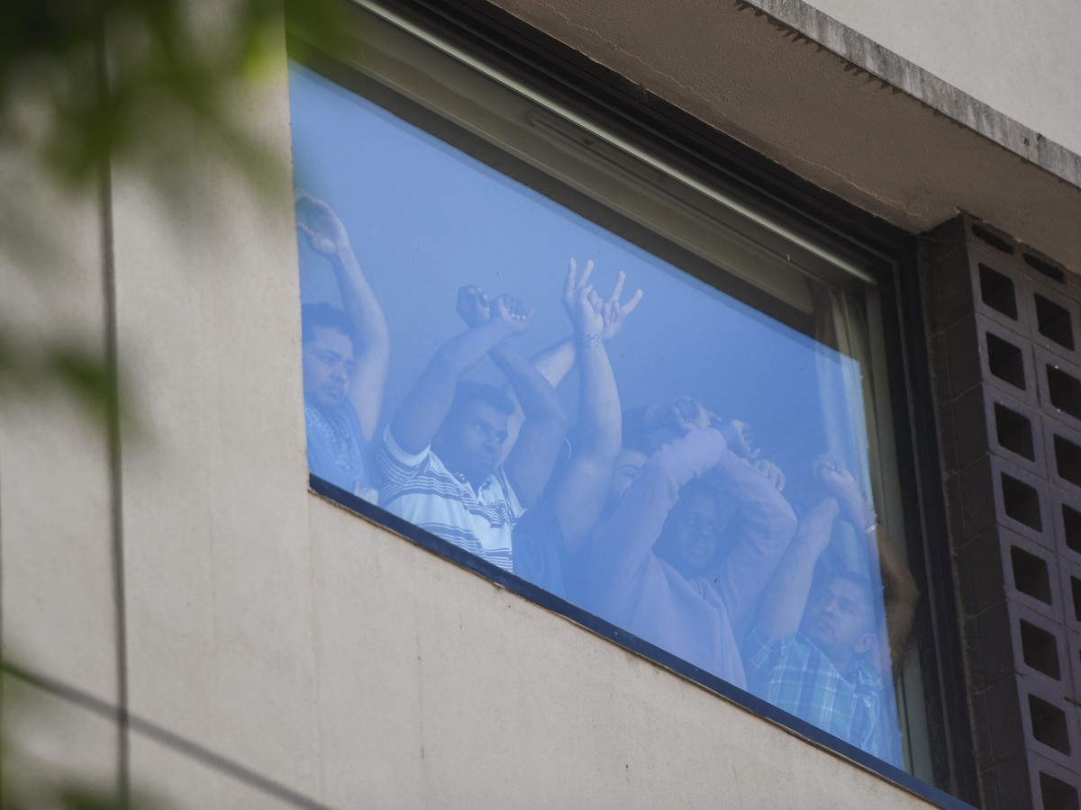 epaselect epa08927513 Refugees gesture towards protesters at the Park Hotel in Melbourne, Australia, 09 January 2021. Around 60 refugees and asylum seekers are being detained at the Park Hotel in Melb ...