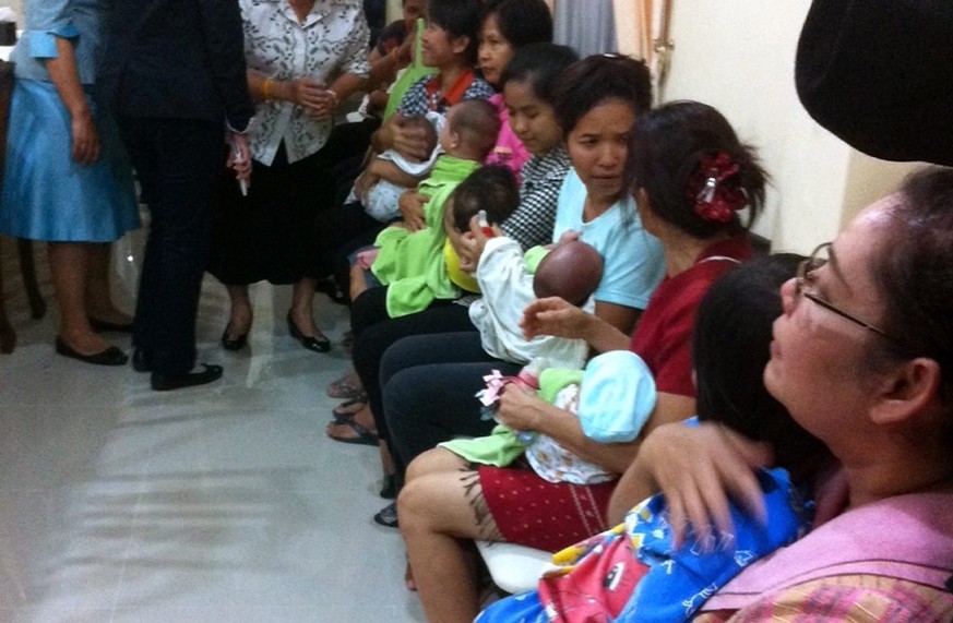 epa04345654 A photo made available on 08 August 2014 shows Thai nannies holding nine suspected surrogate babies after a police raid at a residential apartment and taking them to a government nursing h ...