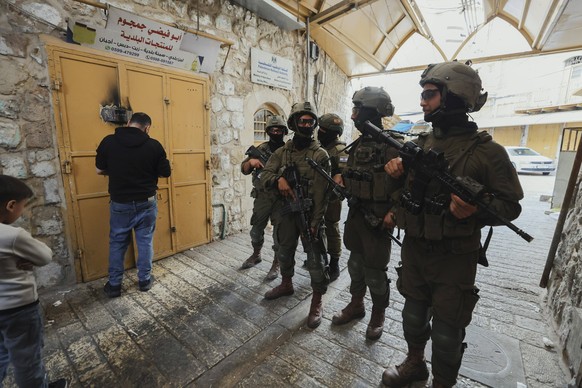Israeli Settlers Tour Hebron Old City Armed Israeli soldiers stand while a Palestinian shop owner closes his store during a tour of Israeli settlers unseen in the Old City of Hebron, in the occupied W ...