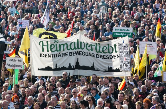 epa05587743 Supporters of the PEGIDA (Patriotic Europeans Against the Islamisation of the Occident) movement carry flags and placards as they gather on the Theatre Square in Dresden, Germany, 16 Octob ...