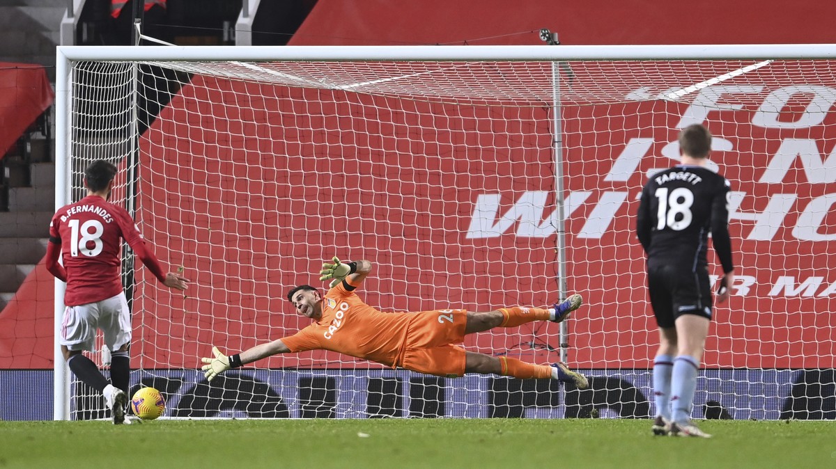 Manchester United's Bruno Fernandes, left scores from the penalty spot for his sides 2nd goal of the game past a diving Aston Villa's goalkeeper Emiliano Martinez during the English Premier  ...