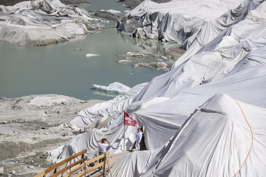 epa10068753 People visit the Rhone Glacier covered in blankets above Gletsch near the Furkapass in Switzerland, 13 July 2022. The Alps oldest glacier is protected by special white blankets to prevent  ...