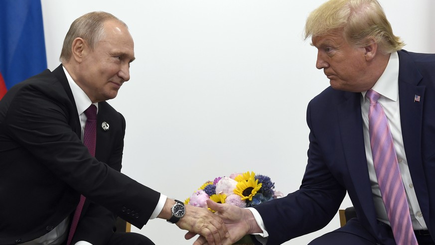 FILE - In this June 28, 2019 file photo, President Donald Trump, right, shakes hands with Russian President Vladimir Putin, left, during a bilateral meeting on the sidelines of the G-20 summit in Osa...