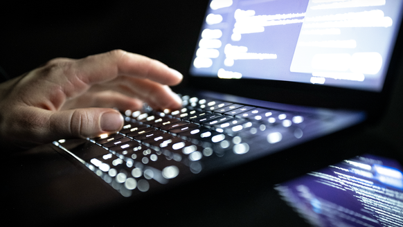 ILLUSTRATION - 14.12.2025, NA, Berlin: Eine Person tippt mit den Fingern auf einer beleuchteten Laptop-Tastatur. (gestellte Szene) (zu dpa: «Ahrweiler warnt nach möglichem Datenleck vor Phishing-Mails ...