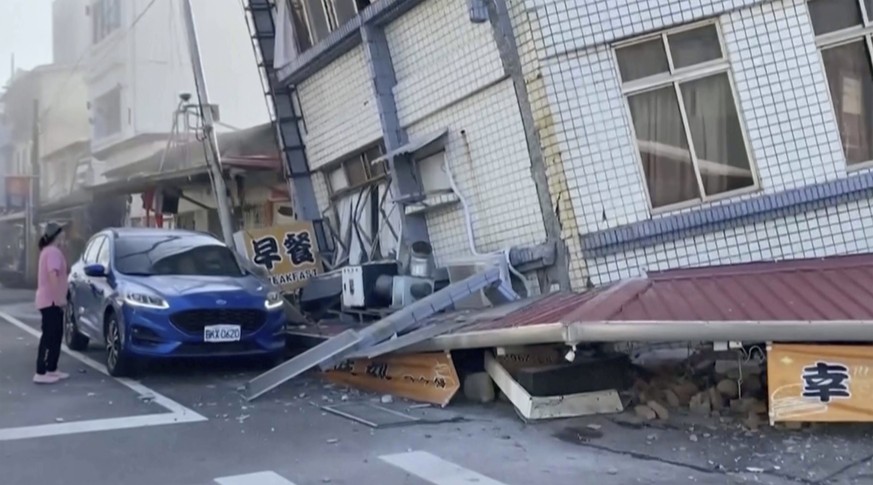 In this image taken from a video footage run by TVBS, a woman stands near a partially collapsed building in Hualien, eastern Taiwan on Wednesday, April 3, 2024. A powerful earthquake rocked the entire ...