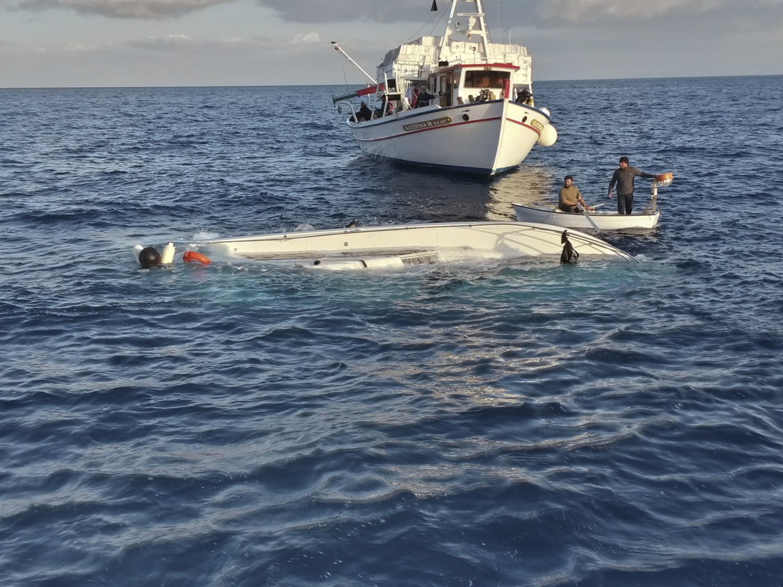 Crew members from a fishing boat look at a capsized vessel in the sea near Samos island, an eastern Aegean island close to the border with Turkey May 5, 2014. Twenty-two migrants drowned and at least  ...