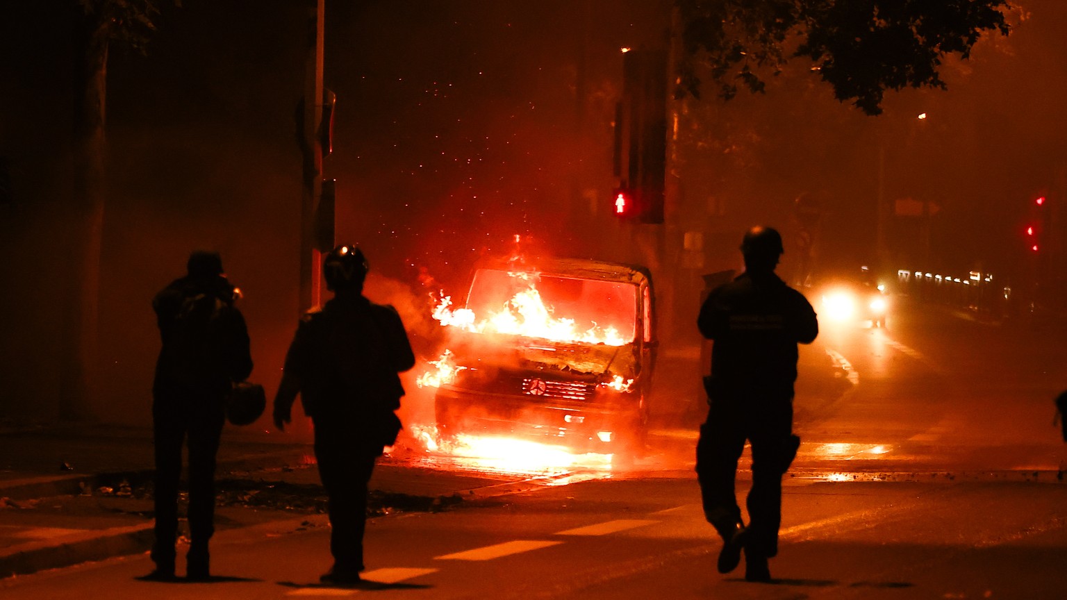 epaselect epa10720120 People walk next to a car burned during clashes between protesters and riot police in Nanterre, near Paris, France, 30 June 2023. Violence broke out all over France after police  ...