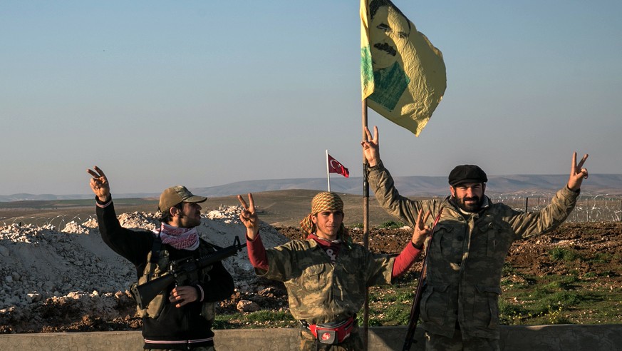 FILE - In this Feb. 22, 2015, file photo, Syrian Kurdish militia members of the YPG make a V-sign next to a drawdng of Abdullah Ocalan, jailed Kurdish rebel leader, in Esme village in Aleppo province, ...