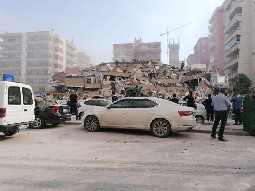 epa08785718 People near a collapsed building after a 7.0 magnitude earthquake in the Aegean Sea in Izmir, Turkey, 30 October 2020. According to Turkish media reports dozens of buildings were destroyed ...