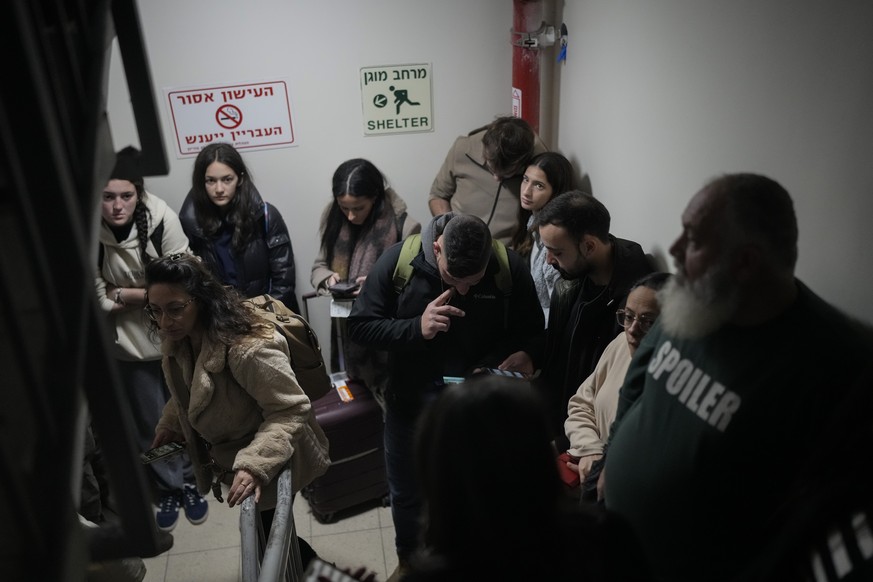 People gather in a shelter after airstrike sirens sounded off in Ben Gurion Airport, near Tel Aviv, Israel, early Friday, Jan. 3, 2024. (AP Photo/Matias Delacroix)