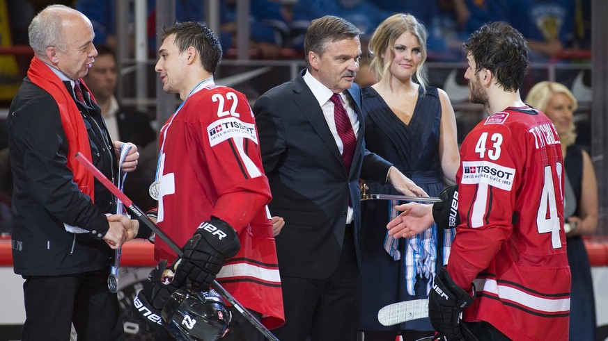 Sportminister Ueli Maurer (links) und René Fasel, der Präsident des internationalen Eishockey-Verbands, überreichen Nino Niederreiter und Morris Trachsler die Silbermedaillen.