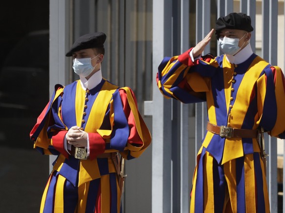 ARCHIV - Zwei uniformierte Gardisten der Päpstlichen Schweizergarde stehen mit Mund-Nasen-Schutz am Eingang zum Vatikan. Foto: Alessandra Tarantino/AP/dpa