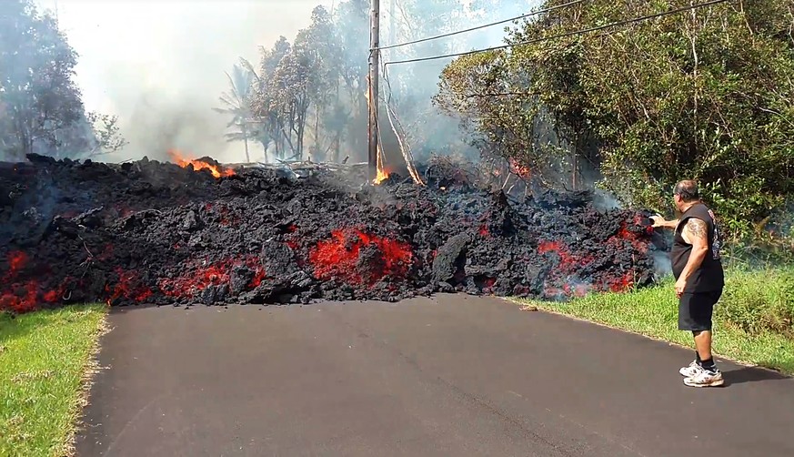 In this photo taken from video an unidentified man gets close to a lava flow advancing down a road in the Leilani Estates subdivision near Pahoa on the island of Hawaii Monday, May 7, 2018. Kilauea vo ...