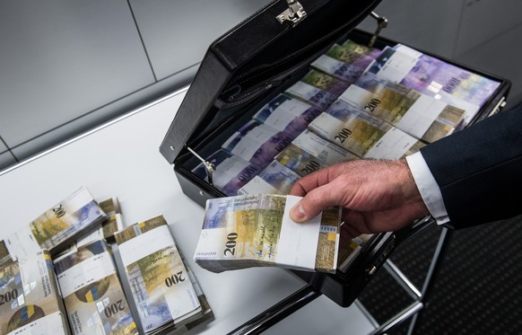 Ein Mann fuellt einen Aktenkoffer mit Tausendernoten und Zweihundert-Franken-Noten neben Schliessfaechern fotografiert in einem Safe einer Bank in Lugano am Mittwoch, 30 November 2016. (KEYSTONE/TI-PR ...