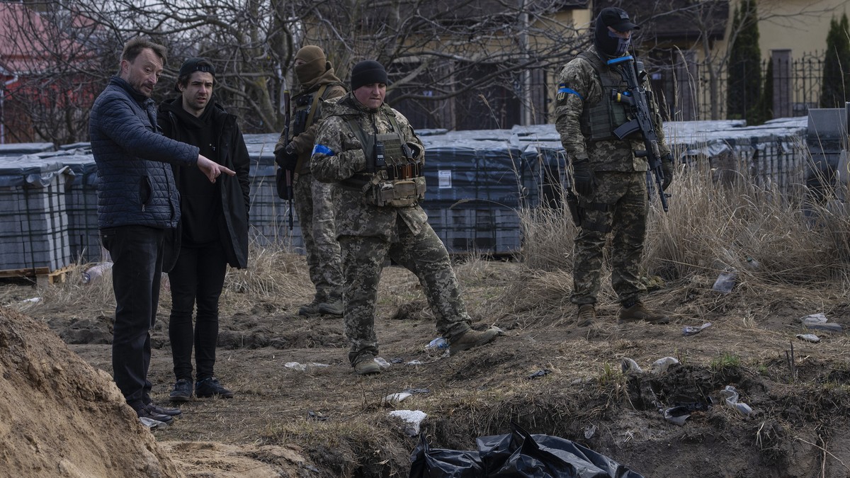 FILE - People stand next to a mass grave in Bucha, on the outskirts of Kyiv, Ukraine, April 4, 2022. The Kremlin and Russian state media are aggressively pushing a baseless conspiracy theory blaming t ...