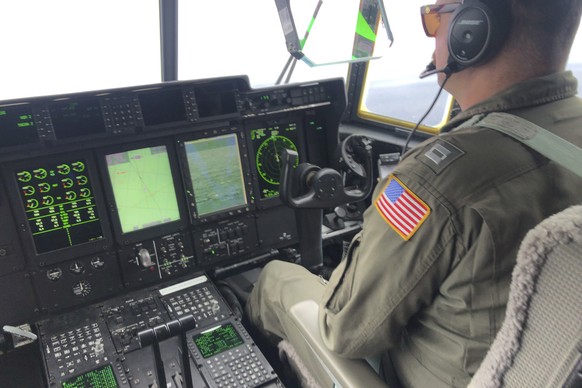 In this image provided by the U.S. Coast Guard, a crew member sits aboard a Coast Guard HC-130 Hercules airplane based at Coast Guard Air Station Elizabeth City, N.C., as it flies about 900 miles East ...