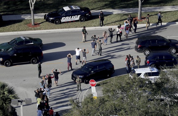 CORRECTS SPELLING TO MARJORY NOT MARJORIE Students hold their hands in the air as they are evacuated by police from Marjory Stoneman Douglas High School in Parkland, Fla., on Wednesday, Feb. 14, 2018, ...