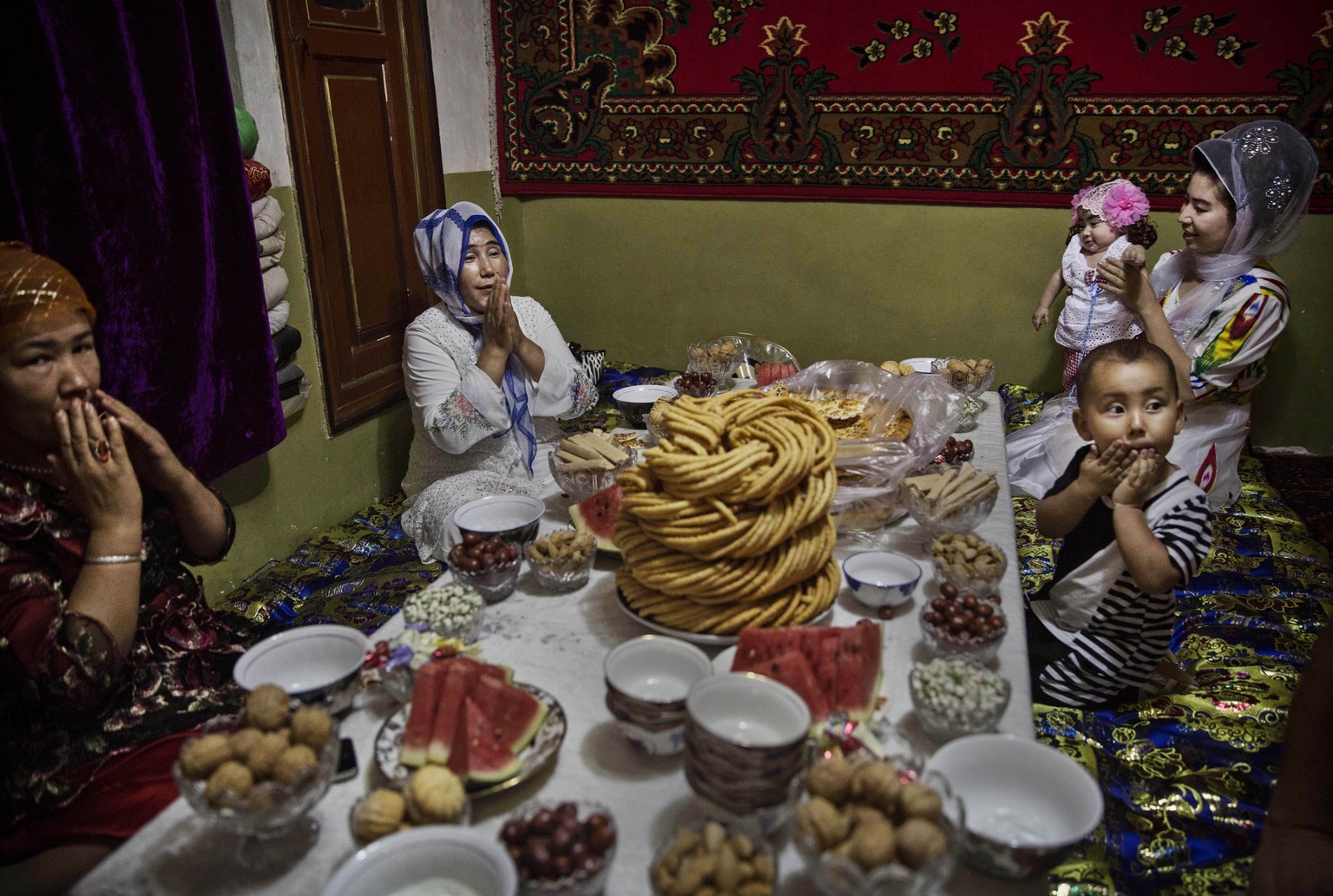 Gebet vor dem Essen: Uigurische Familie beim Eid al-Fitr, dem Fest des Fastenbrechens am Ende des Ramadans. &nbsp;