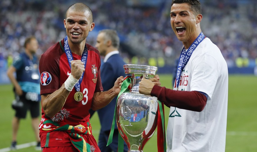 Portugal&#039;s Cristiano Ronaldo, right, and Pepe celebrate with the trophy at the end of the Euro 2016 final soccer match between Portugal and France at the Stade de France in Saint-Denis, north of  ...