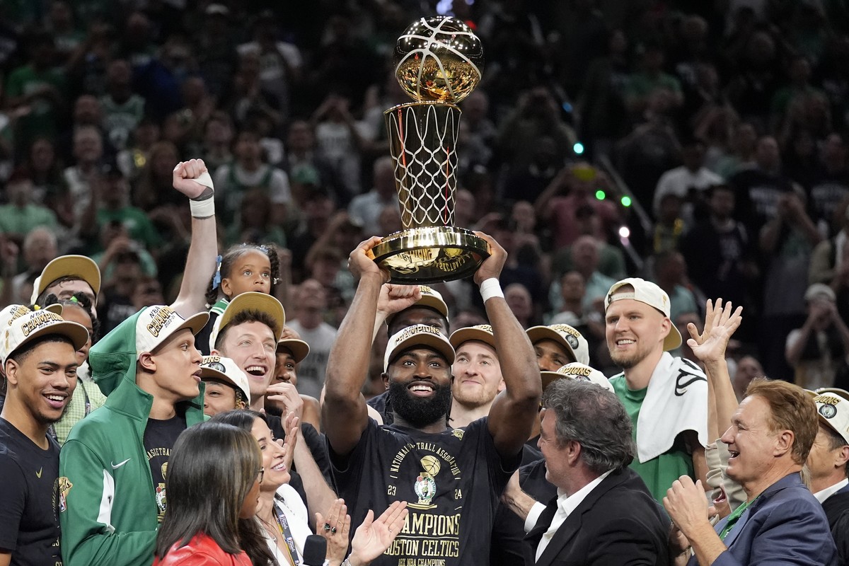 Boston Celtics guard Jaylen Brown, center, holds up the Larry O'Brien Championship Trophy as he celebrates with the team after they won the NBA championship with a Game 5 victory over the Dallas  ...