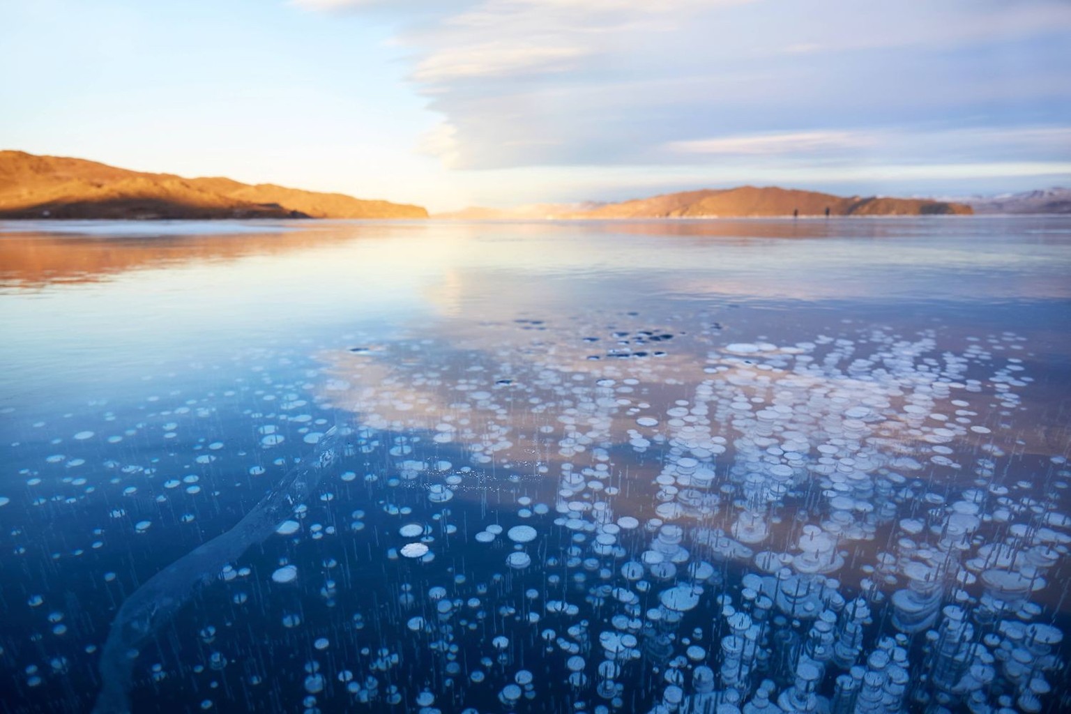 Gefrorener Baikalsee an einem Wintertag. Transparentes glattes Eis mit Methanblasen. Nat�rlicher Hintergrund. Frozen Lake Baikal on a winter day. Transparent smooth ice with methane bubbles. Natural b ...